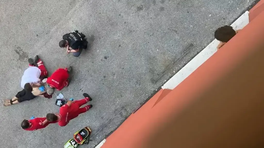 A still image from the one-minute and 14-second video, showing Abderrahim Fakir on the ground, still tied with zip ties at his ankles and arms behind his back. Around him are 4 Red Cross rescuers.