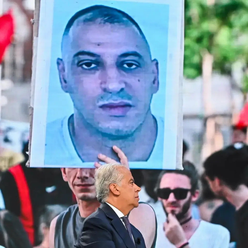Minister Matteo Piantedosi and Fakir's photo on a screen during a demonstration.